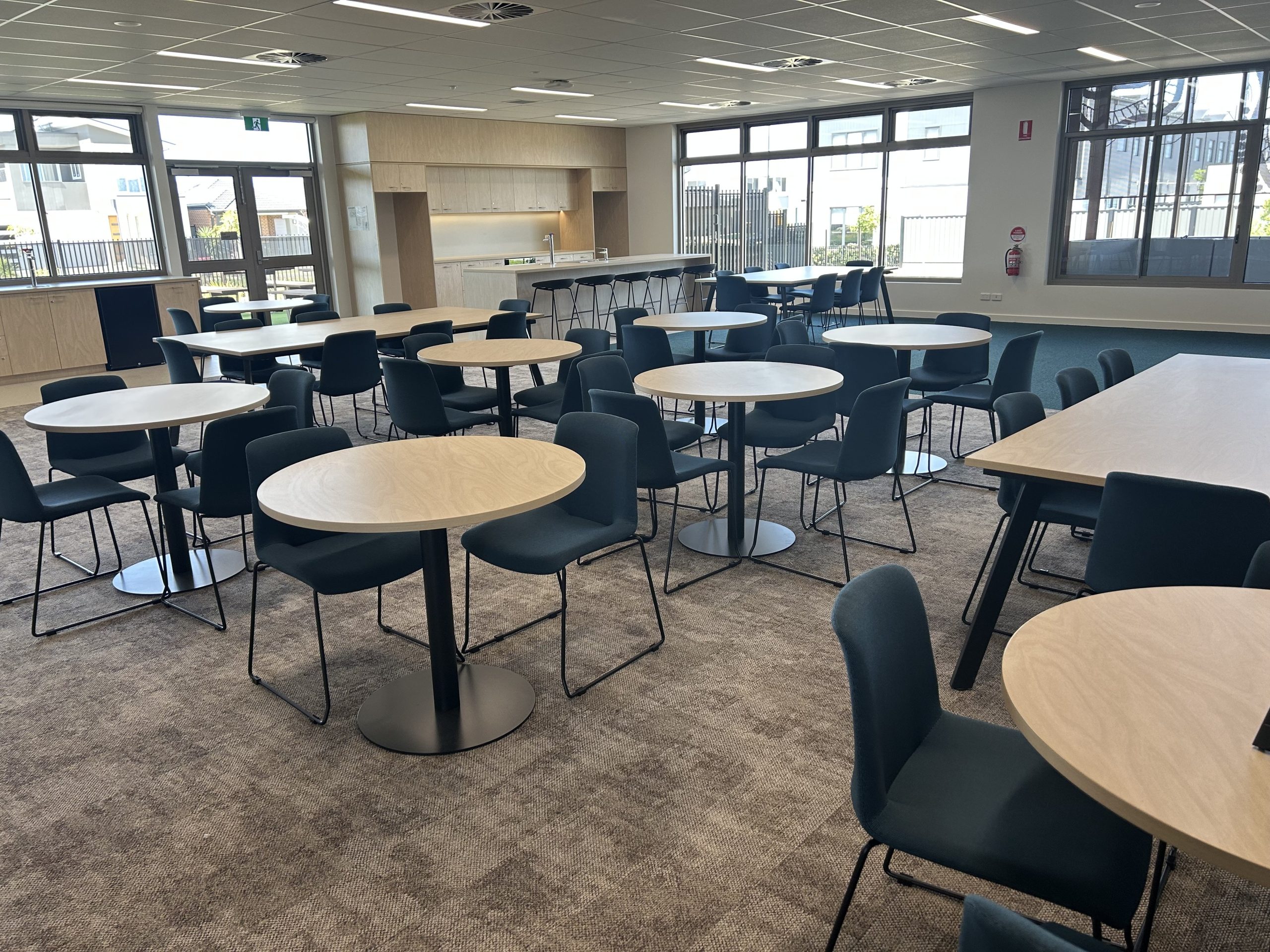 Modern cafeteria with round tables and chairs.