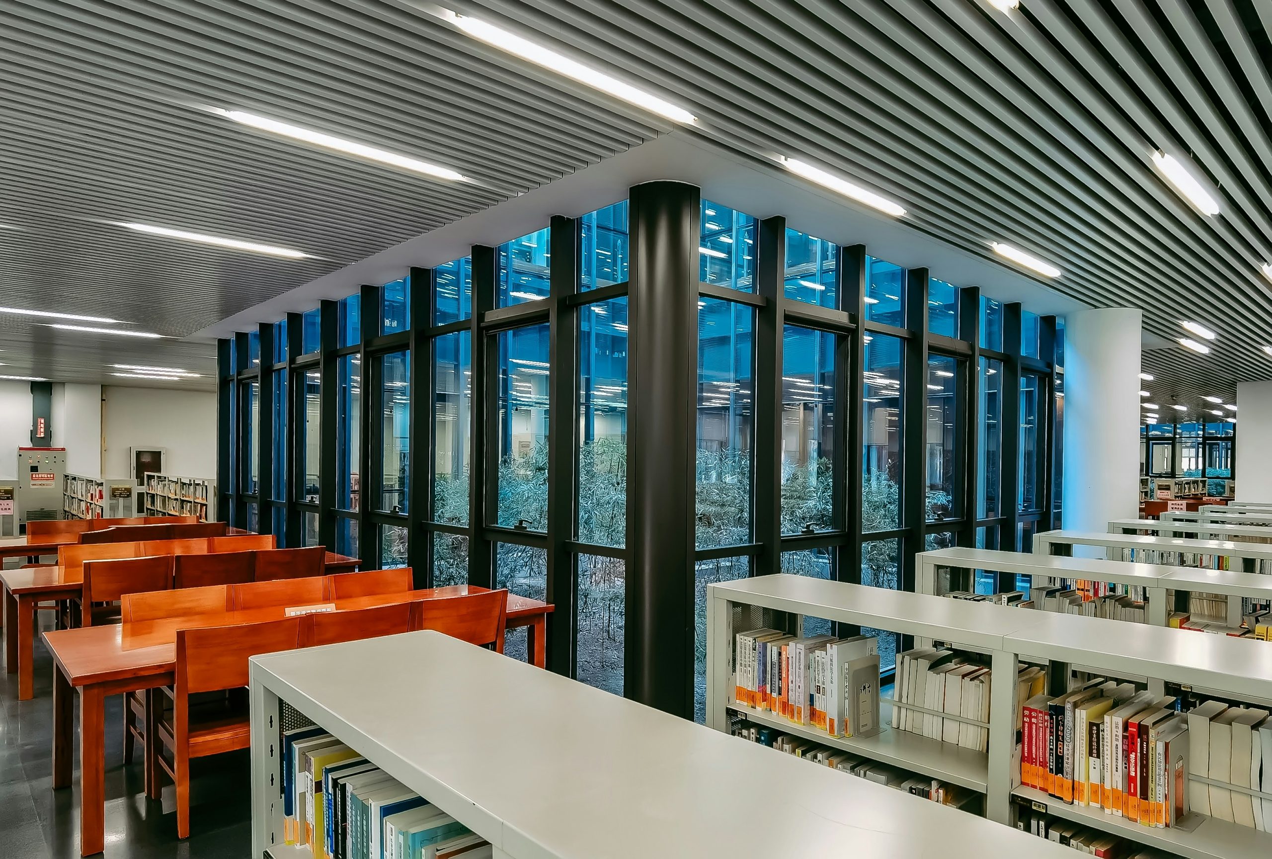 Modern library interior with bookshelves and tables.