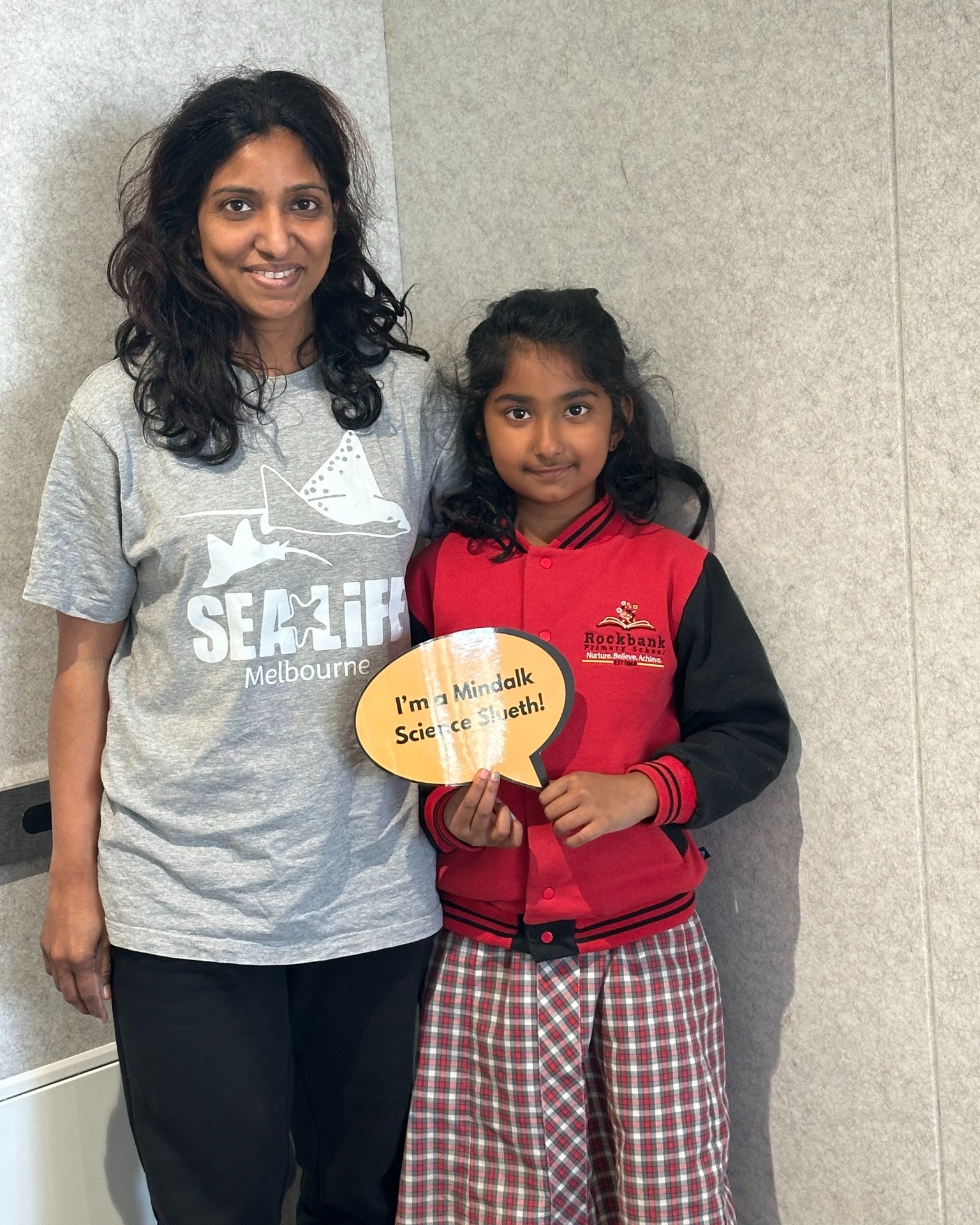 Two people smiling, holding science award.