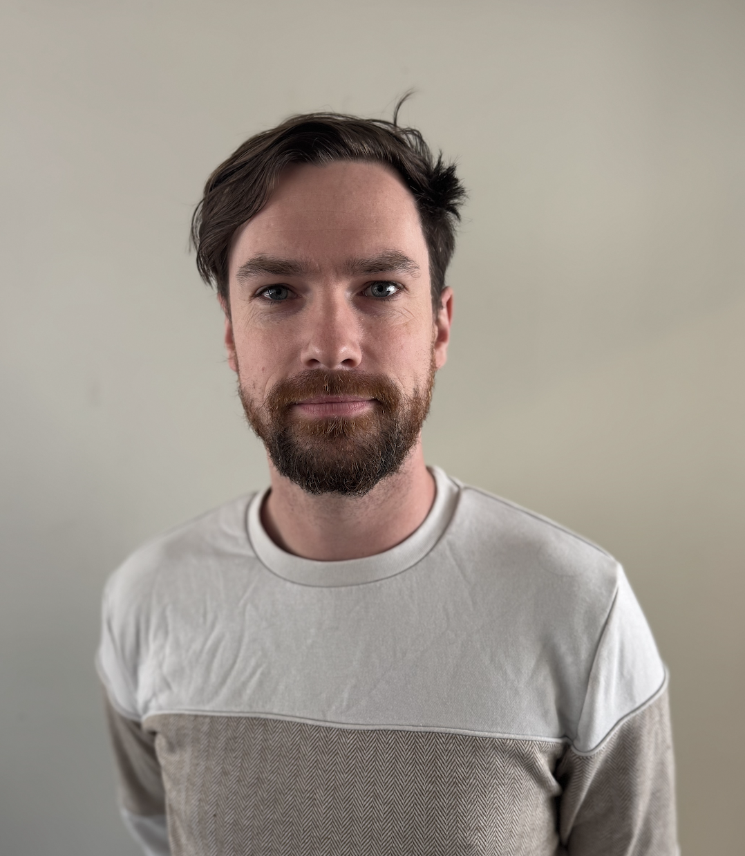 Man with beard wearing a light-coloured jumper.