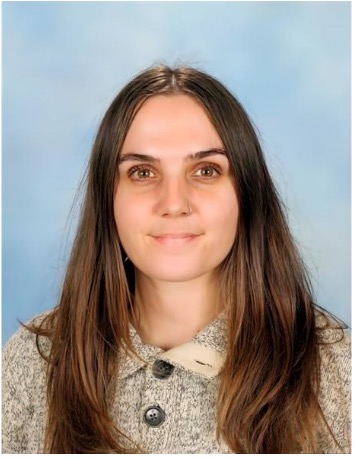 Smiling woman with long hair, wearing a grey sweater.