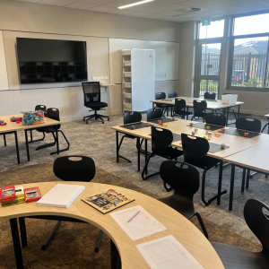 Modern classroom with desks, chairs, and educational materials.